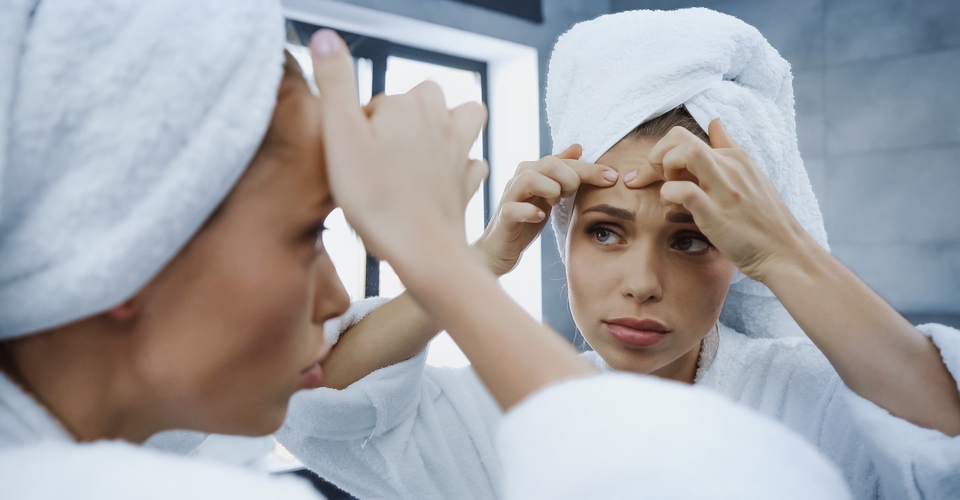 Modelo se olhando no espelho analisando acne